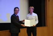 飯島研究科長と、アブレート・グルミレさんの代理で賞状を受け取る圓川研究室のフランクさん 